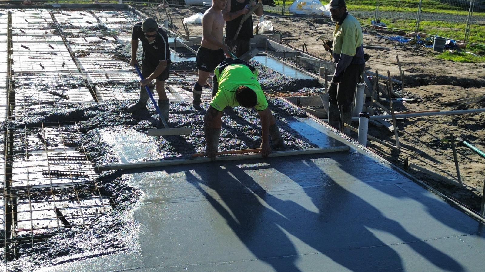 Crew broom finishing a fresh concrete slab pour