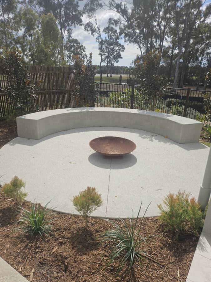 Exposed aggregate fire pit patio with curved concrete bench