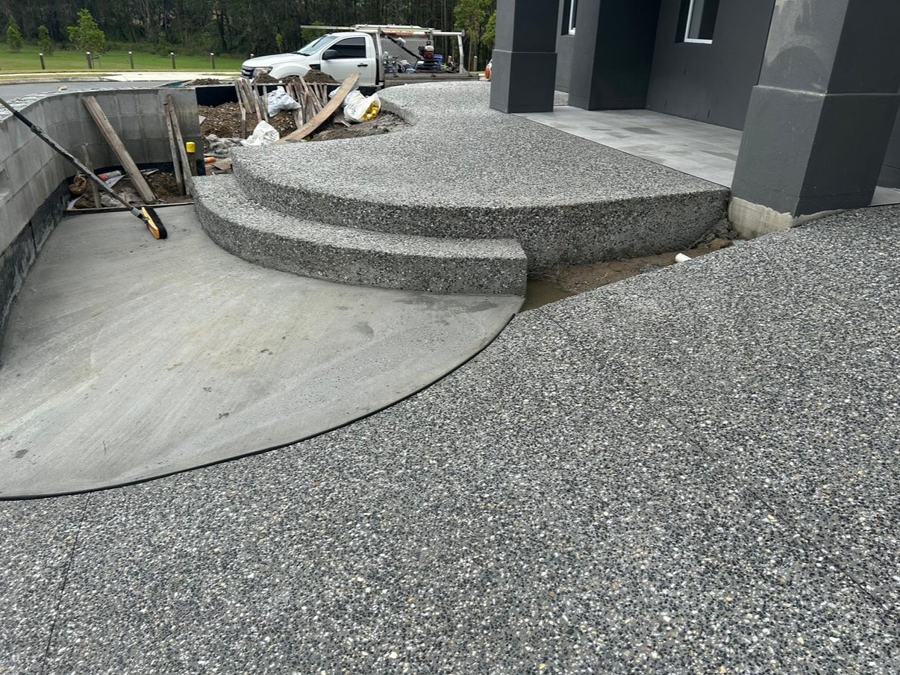 Curved exposed aggregate steps and landing beside modern home