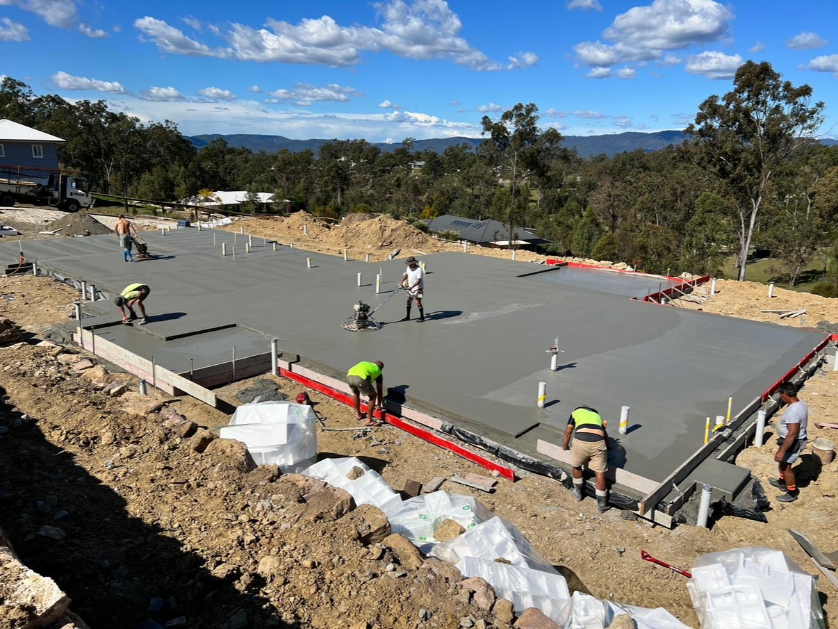 Crew finishing a large house slab pour on a hillside block