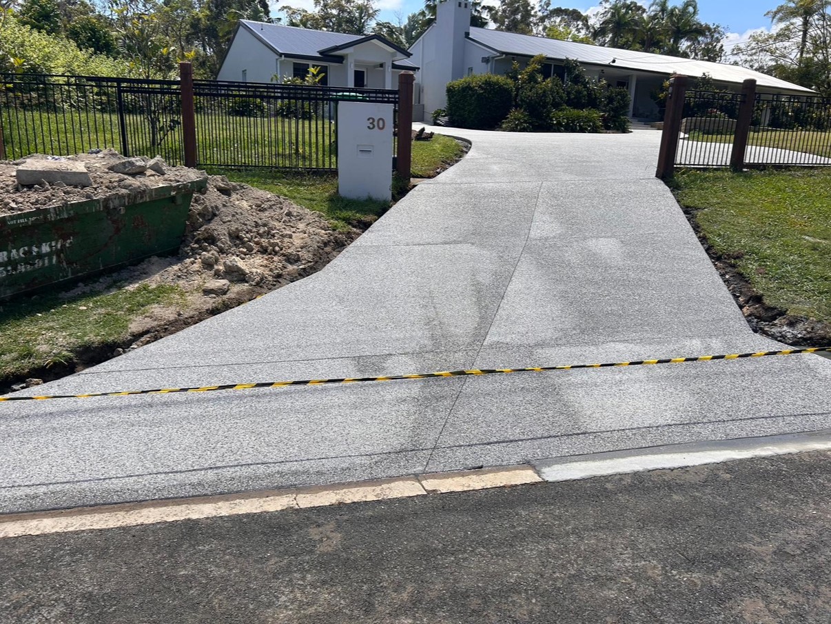 Curved exposed aggregate driveway leading to a rural-style home