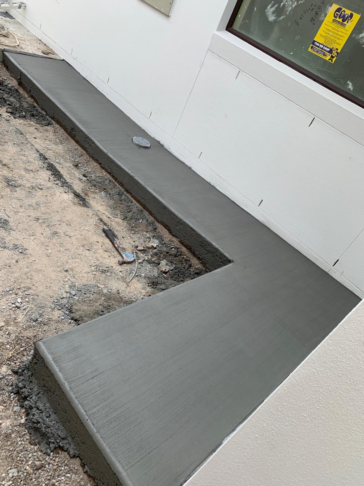 Concrete path along a house wall with a stormwater grate